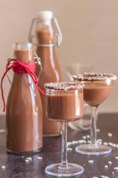 two glasses filled with chocolate pudding next to bottles