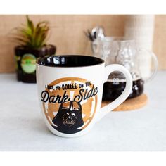 a coffee mug with darth vader on it sitting next to some other items