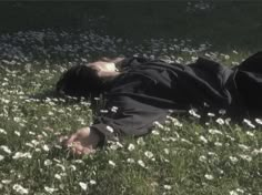 a person laying in the grass with their head on his hands and eyes closed,