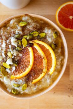 bowl of oatmeal with oranges and pistachios on top