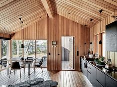 an open kitchen and dining area with wood paneling on the walls, floor, and ceiling