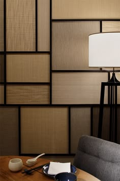 a table with a lamp on top of it next to a wall covered in squares