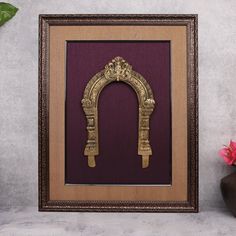 a wooden frame with a gold arch and flowers on the table next to it,