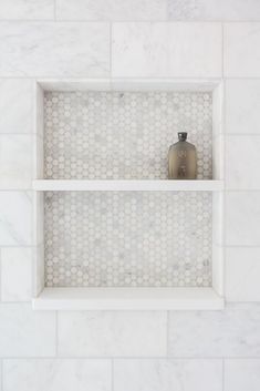 two white shelves with vases on them in a marble tiled wall and floor area