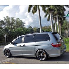 a silver minivan parked in front of palm trees