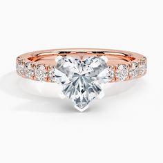 a rose gold engagement ring with a heart shaped diamond in the center and side stones