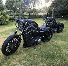 two black motorcycles are parked in the grass