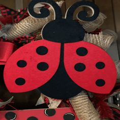 a red and black ladybug wreath is hanging on the front door with burlocks