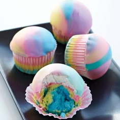 there are three cupcakes with blue and pink frosting in them on a black plate