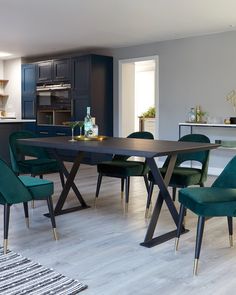 a dining room table with green chairs and an oven in the backround behind it