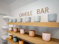 there are many cups on the shelves in this store that is selling candles and candle holders