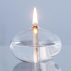 a lit candle in a glass bowl on a reflective surface