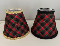 two lampshades decorated with black, red and green tartane fabric are sitting on a white surface