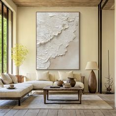 a living room filled with furniture and a large painting on the wall above it's coffee table