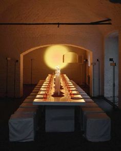 a long table with candles on it in a dimly lit room under a light fixture