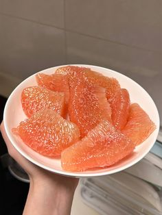 a person holding a white plate filled with sliced oranges