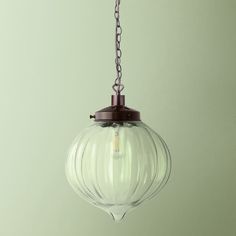 a glass light fixture hanging from a chain on a green wall in a kitchen or dining room