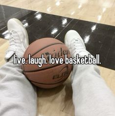 someone is sitting on the floor with their feet up and holding a basketball that says live laugh love basketball