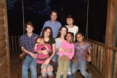 a group of people posing for a photo on a porch at night with the lights on