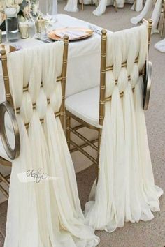 the chairs are covered with white chiffon drapes and gold rimmed napkins