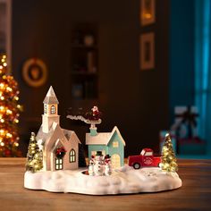 a christmas scene with a small house and car on the table in front of it