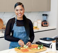 a woman in an apron cutting vegetables on a cutting board