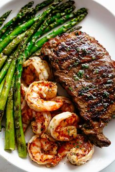 steak, asparagus and shrimp on a white plate with the word grilled