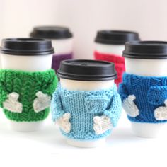 four coffee cups with knitted sweaters on them