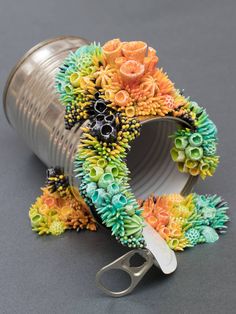 a pair of scissors are sitting next to a tin can filled with fake flowers and leaves