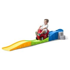 a little boy riding on top of a toy car with a ramp in front of him