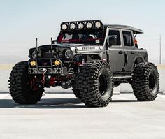 a large gray truck with four tires and lights on it's front end is parked in an empty parking lot