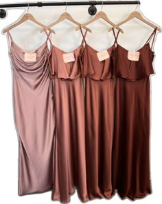 three bridesmaid dresses hanging on a rack