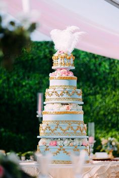 a wedding cake sitting on top of a table covered in flowers and white feather decorations