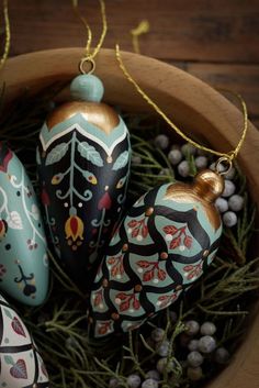 three painted ornaments in a wooden bowl