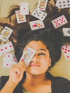 a woman laying on the floor with playing cards in front of her face and eyes