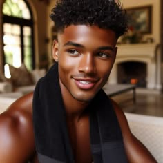 a young man with curly hair wearing a black towel in front of a fire place