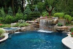 an outdoor pool with waterfall and landscaping