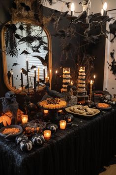 a table topped with lots of halloween food and candles in front of a large mirror