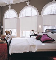 a bedroom with two large windows and a white bed in it's center area