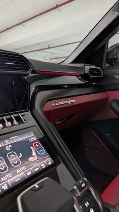 the interior of a sports car with red leather and black trim, including an electronic display