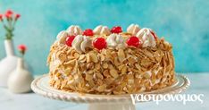 a cake with nuts and cherries on top sitting on a white plate next to a vase