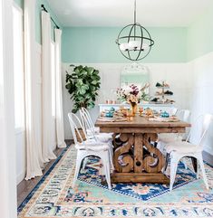 a dining room table with chairs and a rug on the floor in front of it