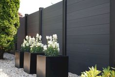 three black planters sitting next to each other in front of a fence