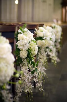 white flowers and greenery line the pews of a church