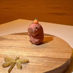 a small pig figurine sitting on top of a wooden table next to a dragonfly