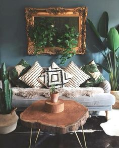 a living room filled with lots of plants next to a couch and coffee table in front of a mirror