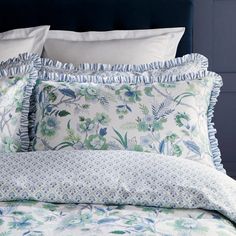 a bed with blue and white sheets and pillows