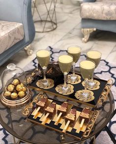 a tray with desserts and drinks on it sitting on a table in a living room