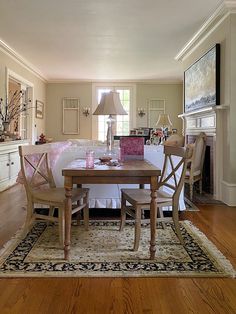 a dining room table with four chairs and a rug on the floor in front of it