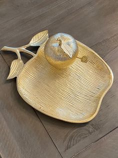 a gold plate with a hat on it sitting on top of a wooden floor next to a wall